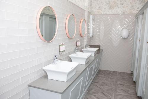 a bathroom with three sinks and two mirrors at Rathkeale House Hotel in Limerick