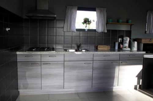eine Küche mit einem Waschbecken und einem Fenster in der Unterkunft De Schaapskooi - Knus Veluws vakantiehuisje in Ede