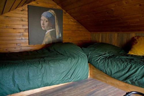 ein Zimmer mit 2 Betten mit einem Bild einer Frau in der Unterkunft De Schaapskooi - Knus Veluws vakantiehuisje in Ede