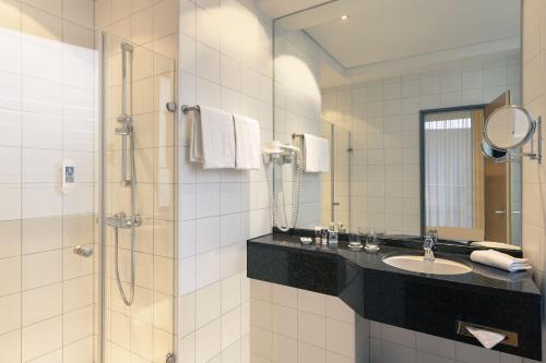 a bathroom with a sink and a shower at Mercure Hotel Aachen Am Dom in Aachen