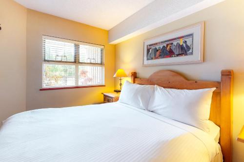 a bedroom with a white bed and two windows at Lake Placid Lodge in Whistler