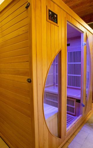 a wooden sauna with a round window and a mirror at Fontána Lipno in Černá v Pošumaví