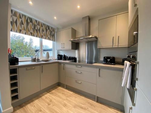 a kitchen with white cabinets and a large window at Meadow House in Stamford