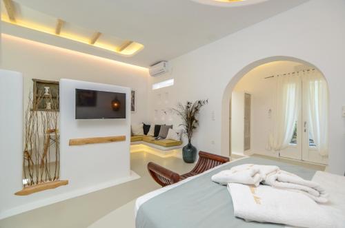 a white bedroom with a bed and a living room at Valena Mare Suites & Apartments in Plaka