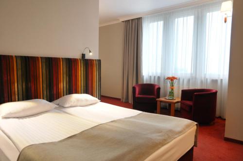 een hotelkamer met een bed en twee stoelen bij Hotel Filmar in Toruń