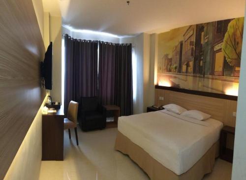 una camera d'albergo con letto, scrivania e sedia di Hotel MJ a Samarinda