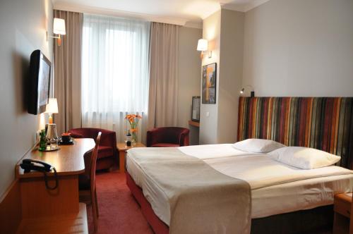 a hotel room with a bed and a desk at Hotel Filmar in Toruń