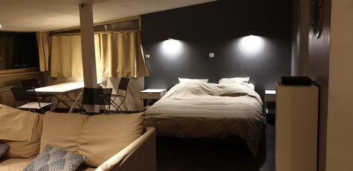 um quarto com uma cama grande e um sofá em Le Coq de Champagne em Dormans