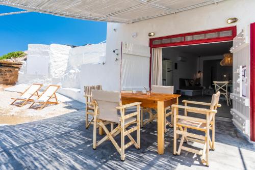 a wooden table and chairs on a patio at Achinos By The Sea Milos in Agia Irini Milos
