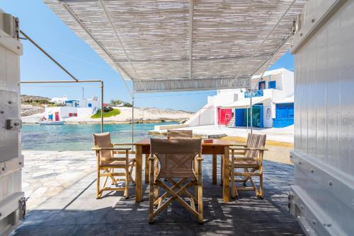 a table and chairs on a patio with a view of the water at Achinos By The Sea Milos in Agia Irini Milos