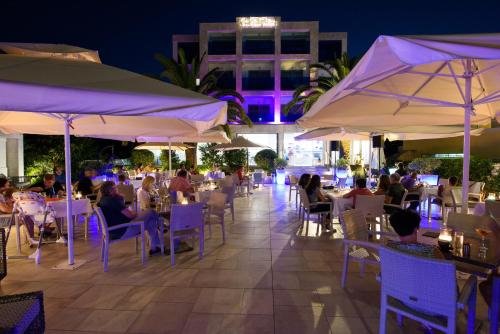 a group of people sitting at tables under umbrellas at TRYP by Wyndham Corfu Dassia in Dassia