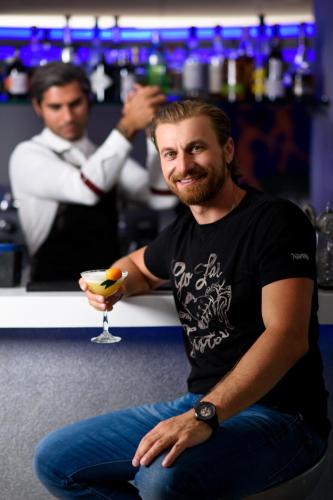 a man sitting on the floor with a drink in a bar at TRYP by Wyndham Corfu Dassia in Dassia