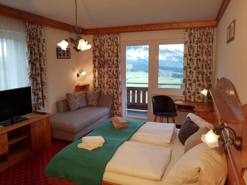 ein Schlafzimmer mit einem Bett und ein Wohnzimmer mit einem Fenster in der Unterkunft Gasthof und Panoramastellplatz Friedburg in Neukirchen am Großvenediger