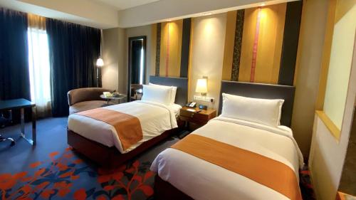 a hotel room with two beds and a chair at Holiday Inn New Delhi Mayur Vihar Noida by IHG in New Delhi