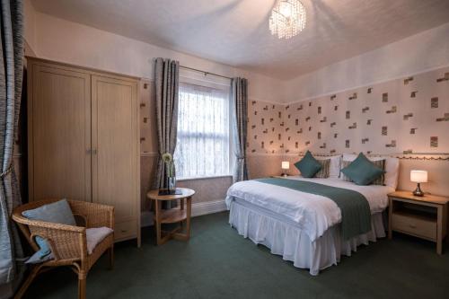 a bedroom with a bed and a chair and a window at Appley Lodge in Shanklin