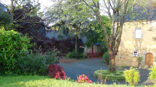 un jardin avec une maison en briques et un arbre dans l'établissement Le Clos des Tilleuls D Day Home, Chambres d'hôtes, Suite avec Sauna Privatif, Suite avec balnéothérapie privative, en supplément option SPA bain à remous, à La Vendelée