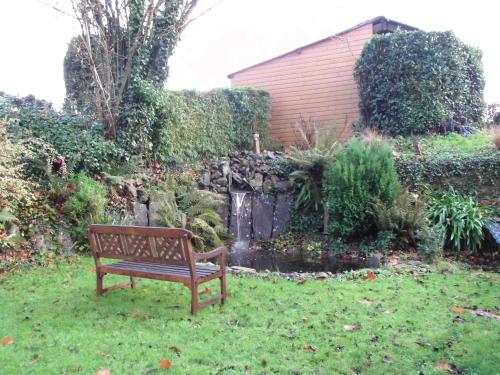 a bench sitting in the grass next to a pond at Le Clos des Tilleuls D Day Home, Chambres d'hôtes, Suite avec Sauna Privatif, Suite avec balnéothérapie privative, en supplément option SPA bain à remous in La Vendelée