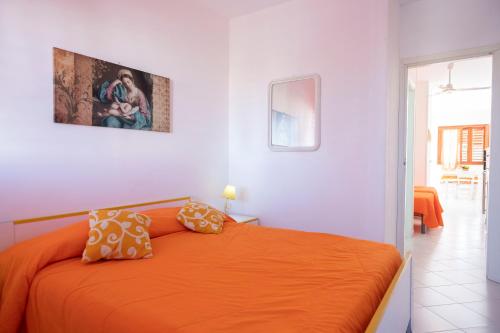 Un dormitorio con una cama naranja en una habitación blanca en Appartamento Sole en San Vito lo Capo