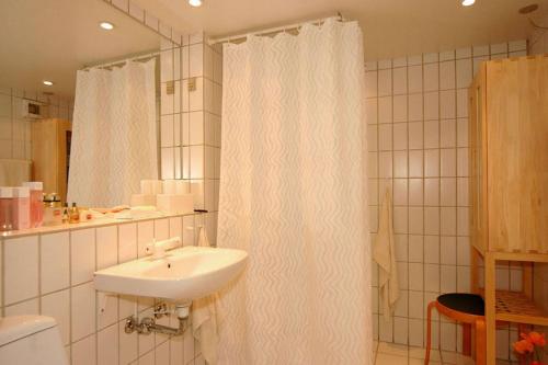 a bathroom with a white shower curtain and a sink at Vigen ferielejligheder in Ebeltoft