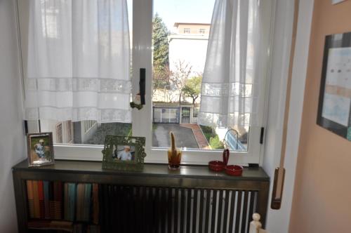 una ventana con cortinas blancas y libros en un radiador en B&B Borsellino, en Cerignola