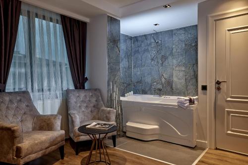 La salle de bains est pourvue d'une baignoire, d'une chaise et d'un lavabo. dans l'établissement The Bold Hotel, à Istanbul