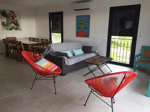un salon avec des chaises rouges et un canapé dans l'établissement Villa grand confort à 500m de la plage de LOZARI, à Palasca
