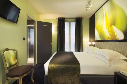 um quarto de hotel com uma cama grande e uma televisão em Hôtel Le Fabe em Paris