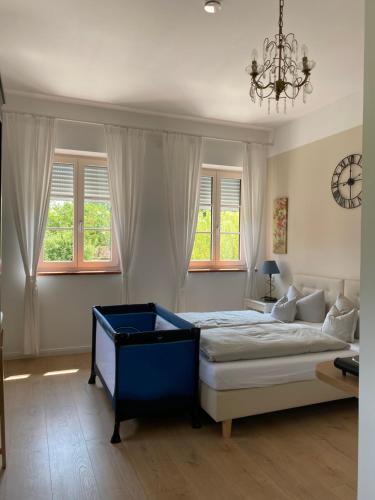 a bedroom with a bed and a chandelier and windows at Landgut zur Mühle in Dorfen