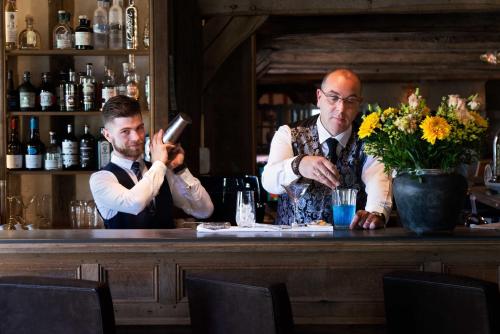 two men sitting at a bar looking at his cell phone at La Ferme Saint Simeon Spa - Relais & Chateaux in Honfleur