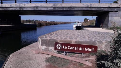 a sign that says be canal oil patch under a bridge at 3 bedroom apartment overlooking river in Agde