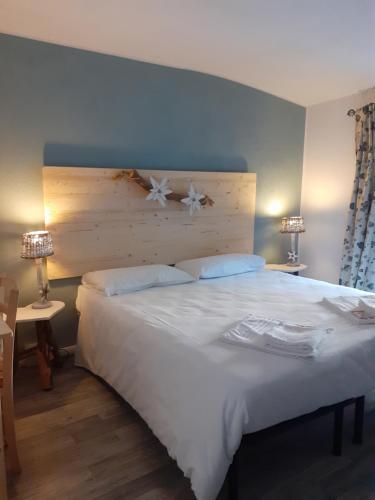 a bedroom with a large white bed with a wooden headboard at La Casetta Del Dahu in Limone Piemonte