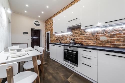 a kitchen with white cabinets and a brick wall at InshiApartments on Grigorenko's square in Lviv