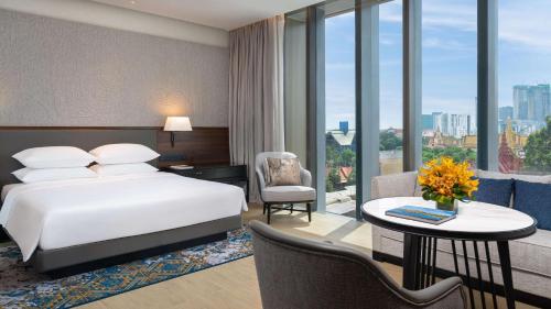 a hotel room with a bed and a desk and a table with a tablektop at Hyatt Regency Phnom Penh in Phnom Penh