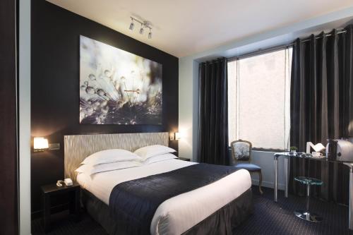 a hotel room with a bed and a painting on the wall at Hôtel Le Fabe in Paris