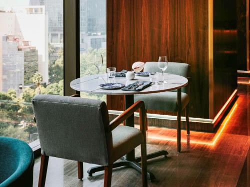 a table and chairs in a room with a window at Sofitel Mexico City Reforma in Mexico City
