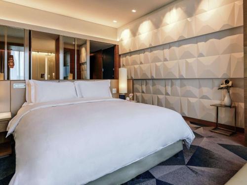 a bedroom with a large white bed and a wall at Sofitel Mexico City Reforma in Mexico City