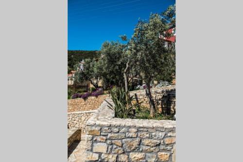 a garden with a stone wall and trees at Apollo Romantic Sea View Villa in Kivérion