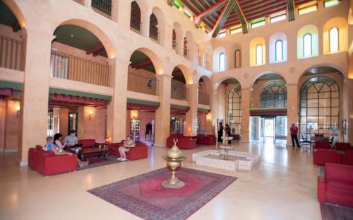 un gran vestíbulo con gente sentada en sillas en un edificio en El Ksar Resort & Thalasso en Sousse