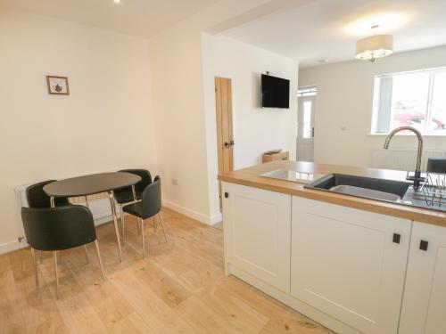 a kitchen with a sink and a table with chairs at One Conway View in Colwyn Bay