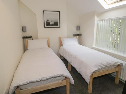 two twin beds in a room with a window at One Conway View in Colwyn Bay