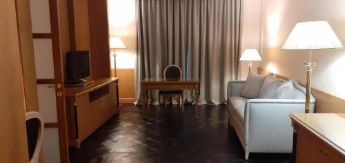 a hotel room with a couch and a television at Grand Hotel De La Ville in Parma