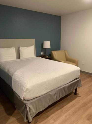 a bedroom with a large bed and a chair at WoodSpring Suites Columbus Urbancrest in Grove City