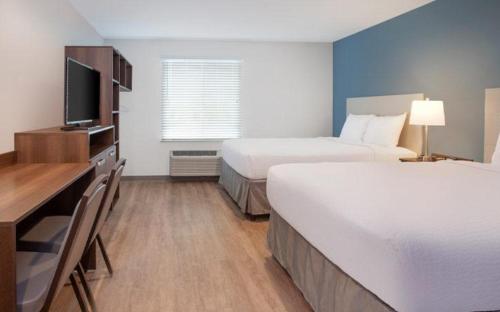 a hotel room with two beds and a flat screen tv at WoodSpring Suites Columbus Urbancrest in Grove City