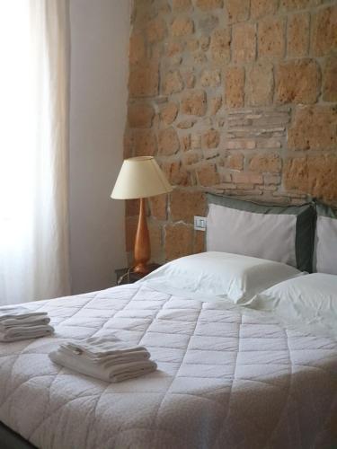 a bedroom with a white bed with a brick wall at Appartamento Mia in Orvieto