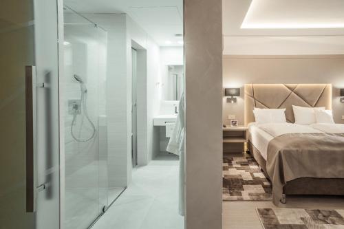 a bedroom with a bed and a bathroom with a shower at Hotel Eden Garden Spa in Câmpulung Moldovenesc
