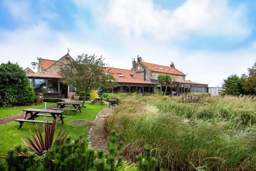 a building with picnic tables in the grass at The Stables - The Inn Collection Group in Whitby