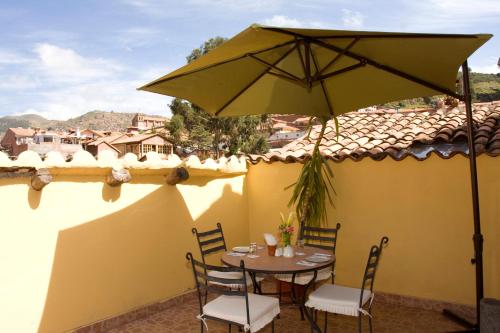 a table and chairs with an umbrella on a roof at Hotel & Mirador Los Apus in Cusco