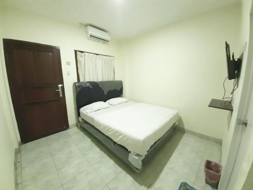 um pequeno quarto com uma cama e uma porta em KK Wisma Berkat em Jakarta