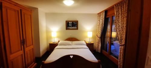 a small bedroom with a bed and two lamps at Appartement et studio, Val d'illiez in Val dʼIlliez
