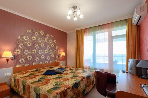 a bedroom with a bed and a desk and a window at Evridika Apartments in Nesebar